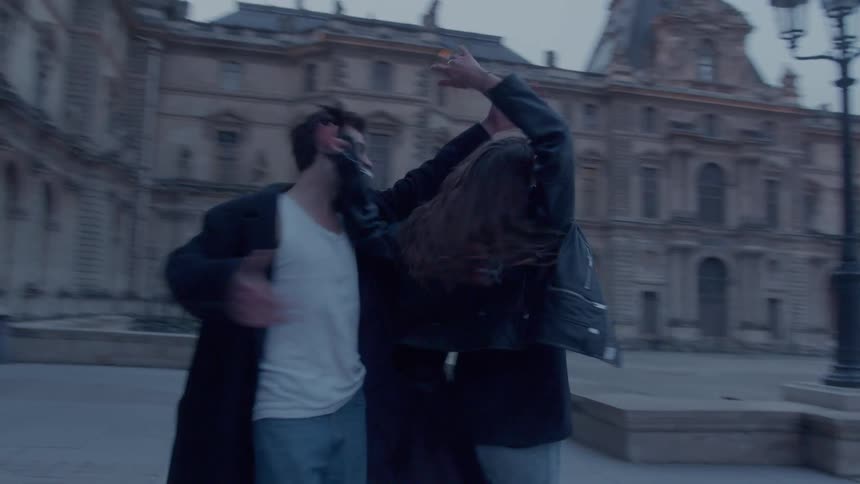 An excited young couple dancing happily outside the louvre