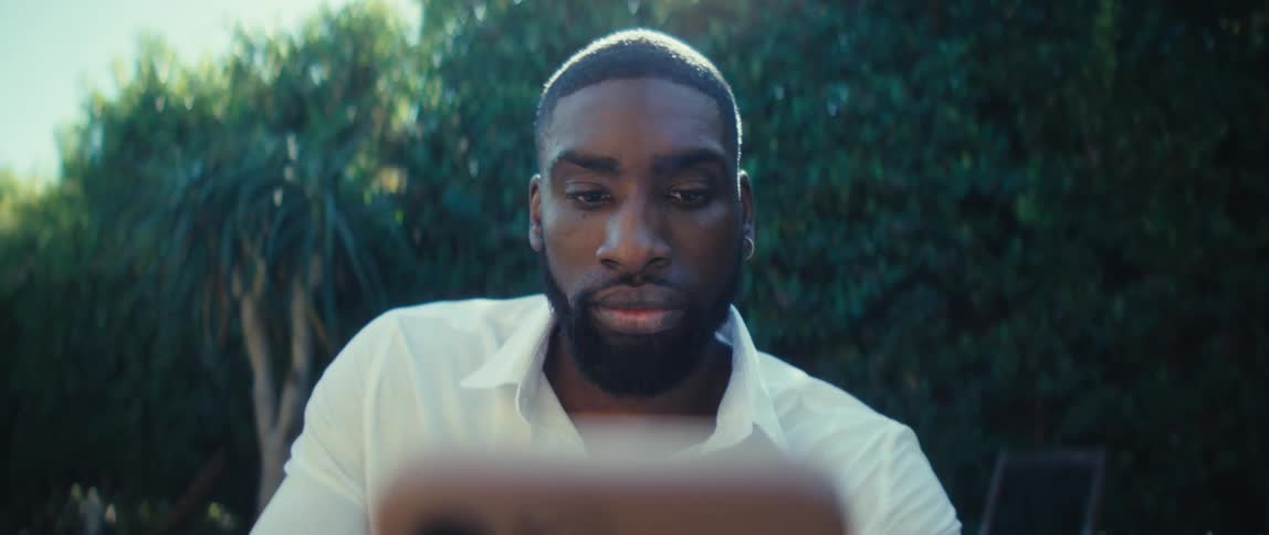 A man in a backyard holds up a smart phone in front of him smiling and waving when a video call starts