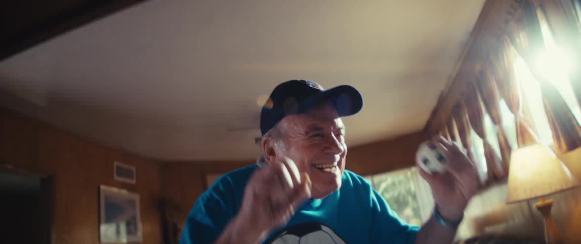 An elderly man cheers as he looks at a screen