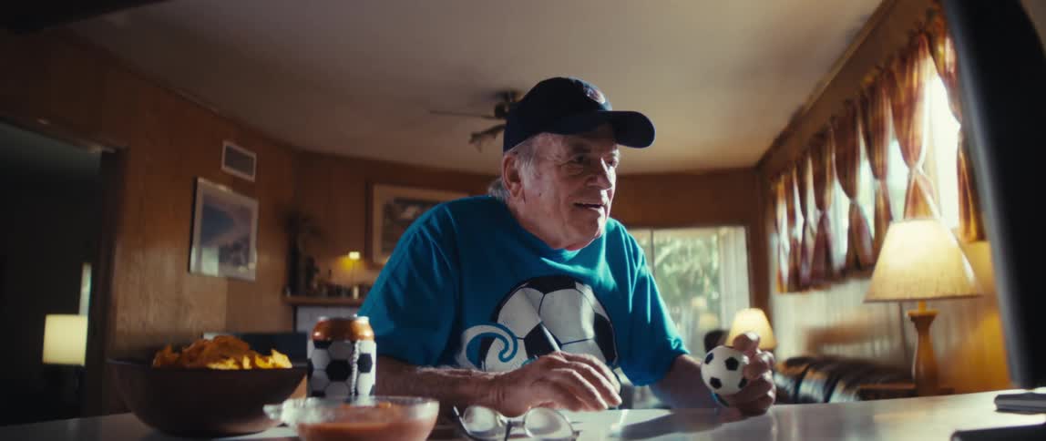 The man cheers while watching a game on the television