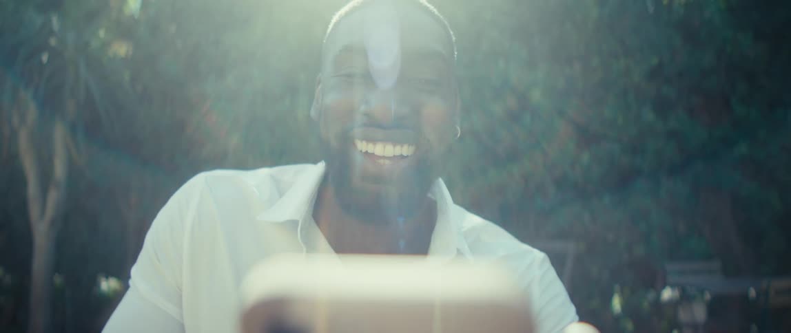 The man smiles and talks to his cell phone