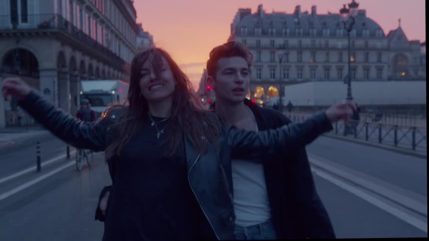 The couple walk together past traffic on the street