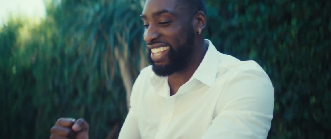 Man sitting outside at a table holding his phone cheers and celebrates