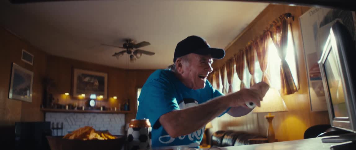 The man is cheering at the television at home