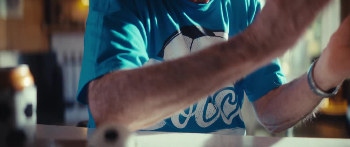 An elderly man wearing a soccer fan t shirt excitedly claps his hands and cheers