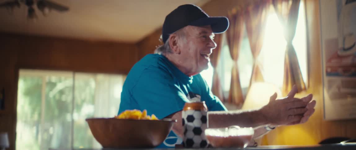 A man cheering while watching football on tv