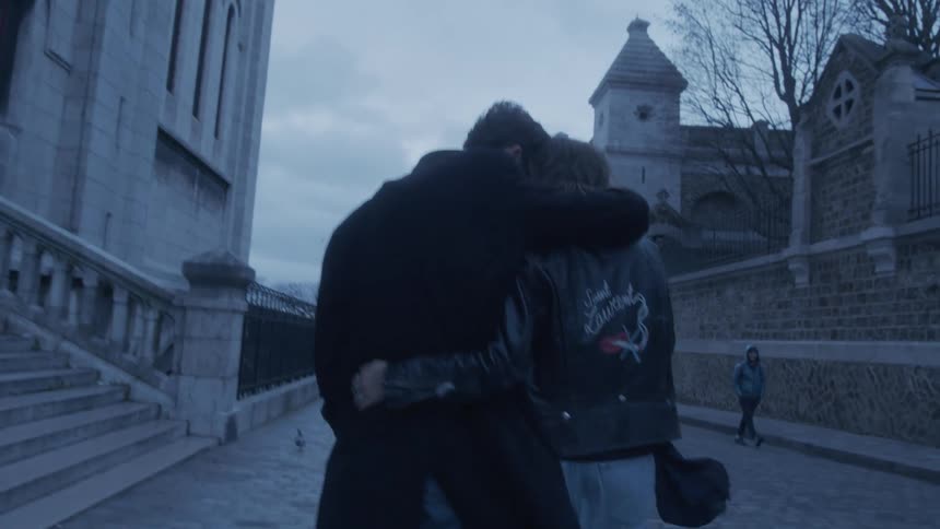 A young couple walking on a street in paris with their arms around each other