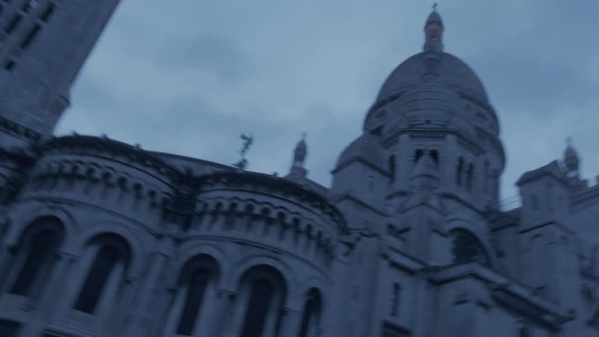 Sacrcur basilica in paris seen from a low angle emphasizing its grand architecture beneath a cloudy sky