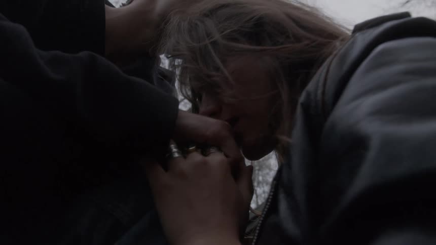 A young couple outdoors shares a moment with the young man kissing the young woman on the head at midday