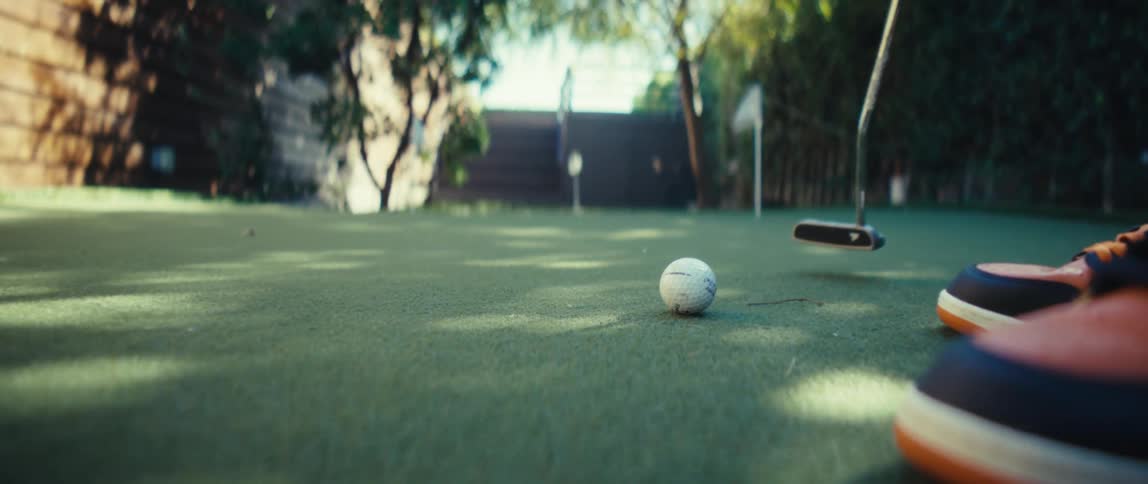 A person uses a golf club to put a golf ball at a putting range