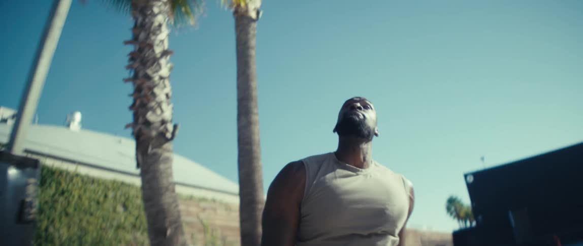 Black bearded man playing basketball and cheering after scoring a point outdoors during day time