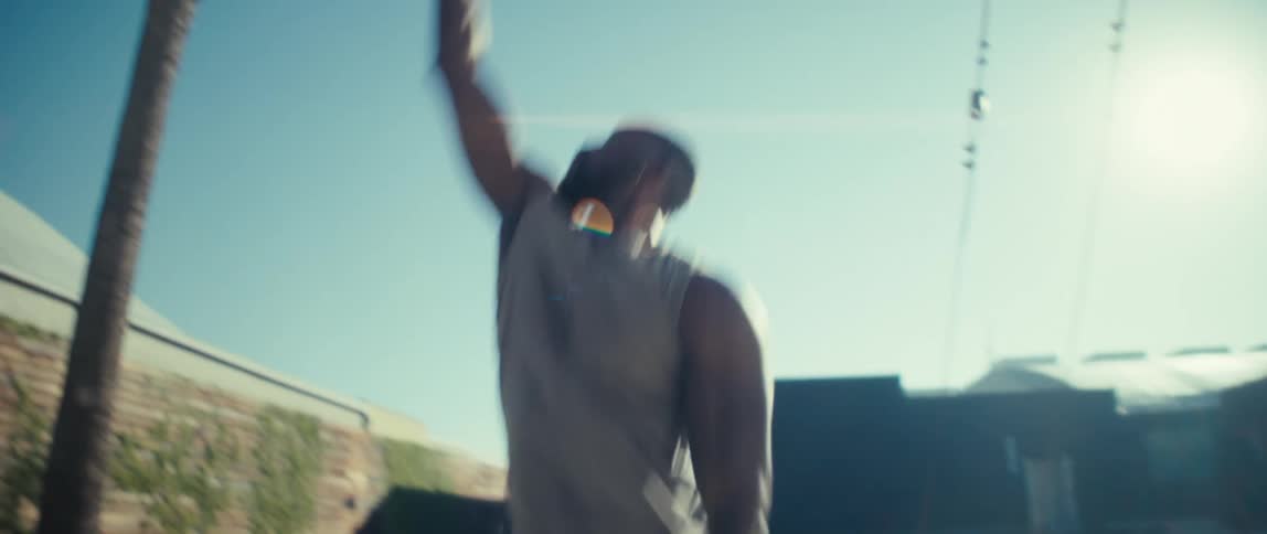 A basketball player trains alone shooting the ball into the hoop on a sunny day