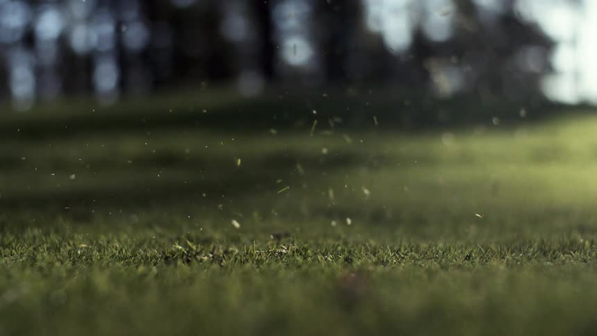 A golf club hits a ball hard lifting up a big chunk of grass with it