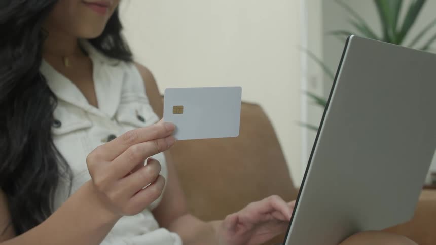 A woman taps on a screen while holding a credit card
