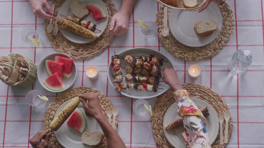 Table set with corn on the cob skewers and watermelon slices