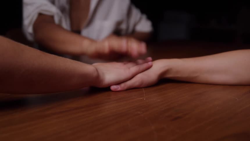 Hands join together on the table in a gesture of support and solidarity