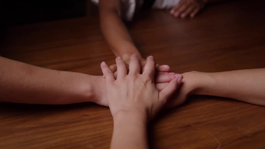 Three people putting their hands together in a pile one hand at a time
