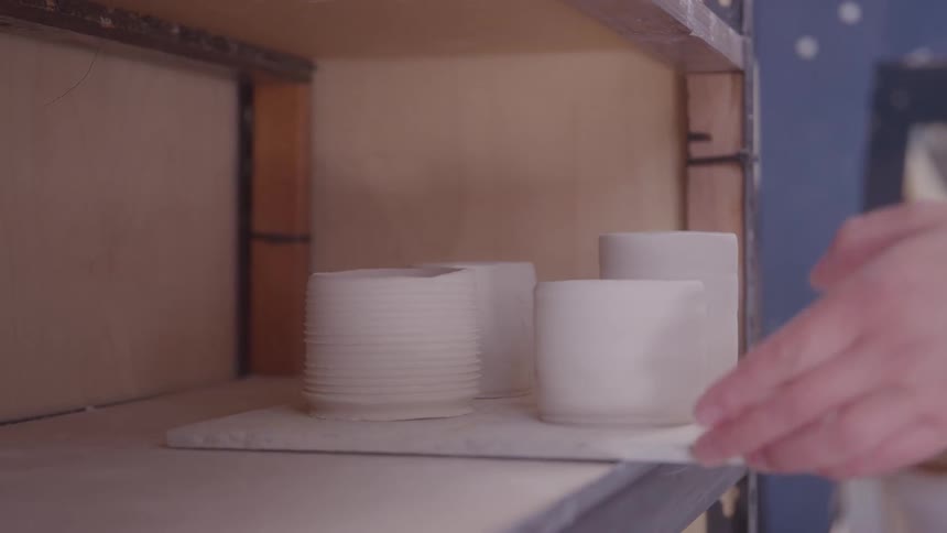 Womans hands lifting a tray with cups off the counter