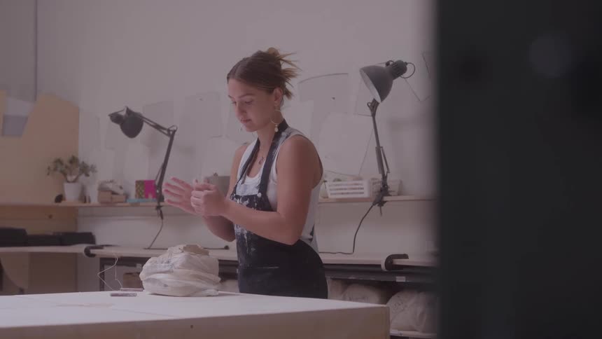Woman kneading clay on a table in a pottery studio