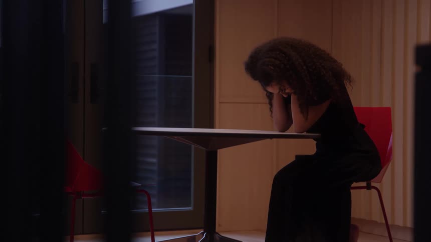 The woman brushes her hair back at the table