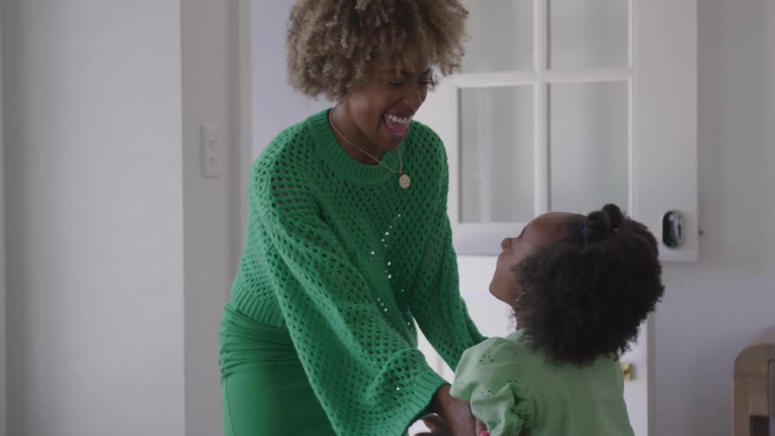 Woman smiling while playing with a girl dressed in green