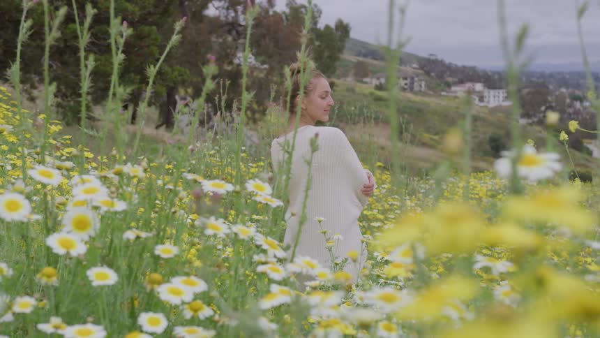 A woman stands quietly on a mountain among wildflowers