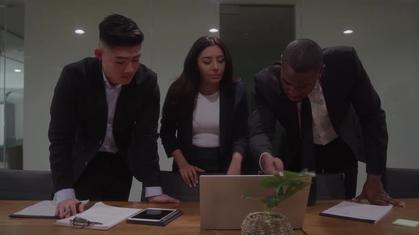 Three coworkers analyzing something on a laptop during a meeting