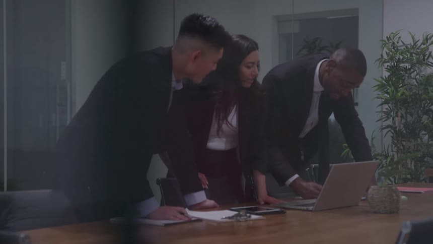 Businesspeople stand during a meeting while one of them writes