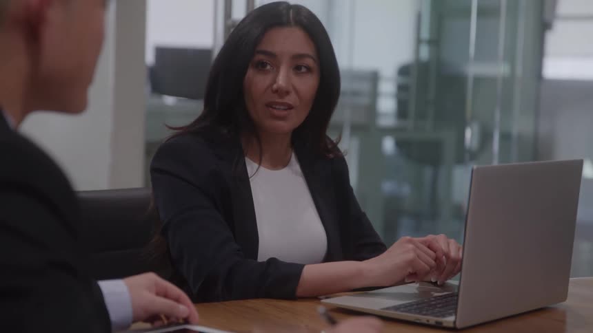 A couple people talk at a desk