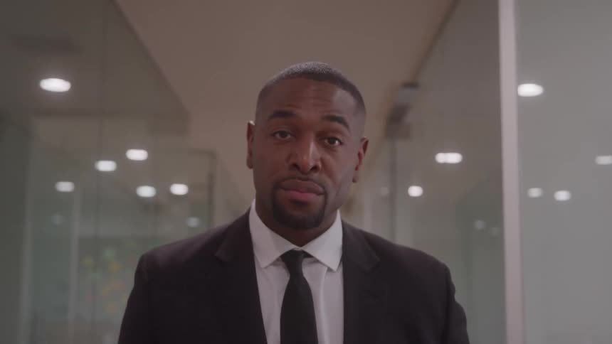 Man in a suit and tie looking intently in an office hallway