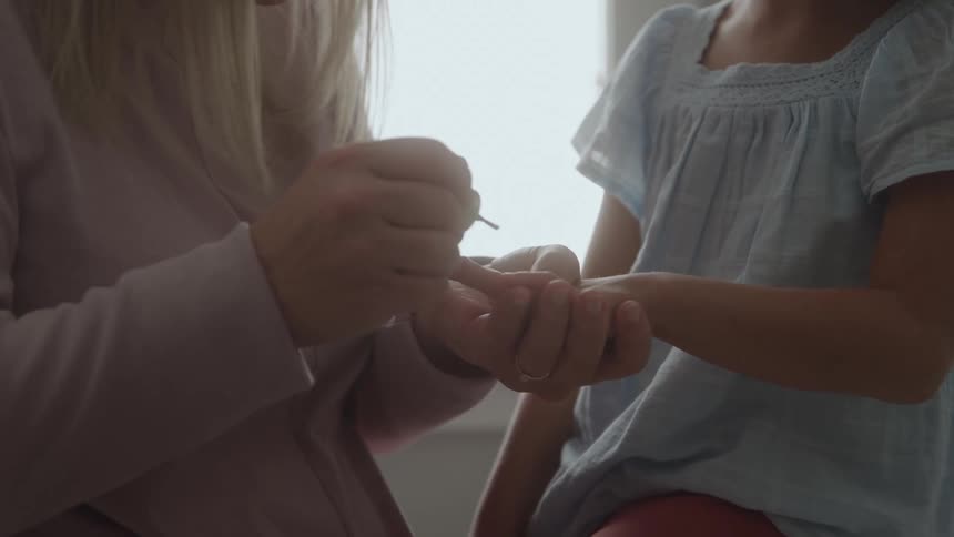 Woman painting a childs nails as she sits beside her