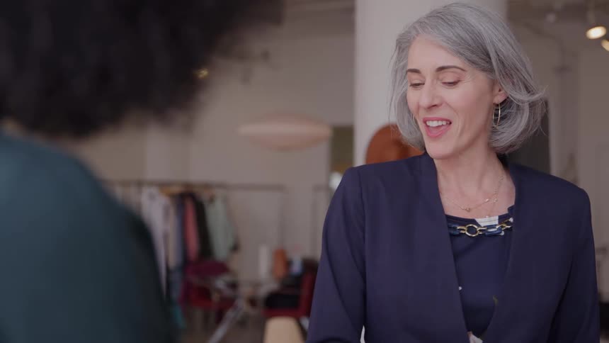 An older female is talking to another female in a clothing boutique