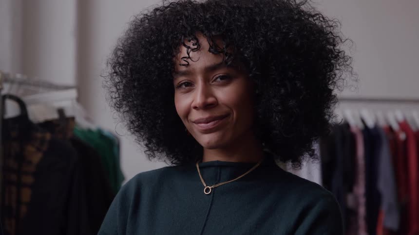 A woman smiles as she stands inside a clothing store
