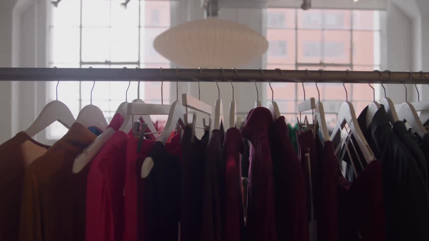 Numerous pieces of clothing are all hanging from hangers on a rack
