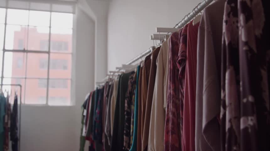 Clothes hanging on racks near a window in a fashion studio