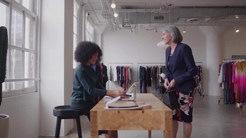 Female customer and the clothes store clerk laugh and talk as the customer pays
