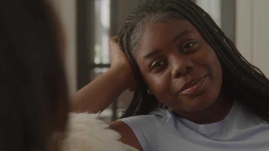 Smiling young woman reclining on the couch during a relaxed conversation