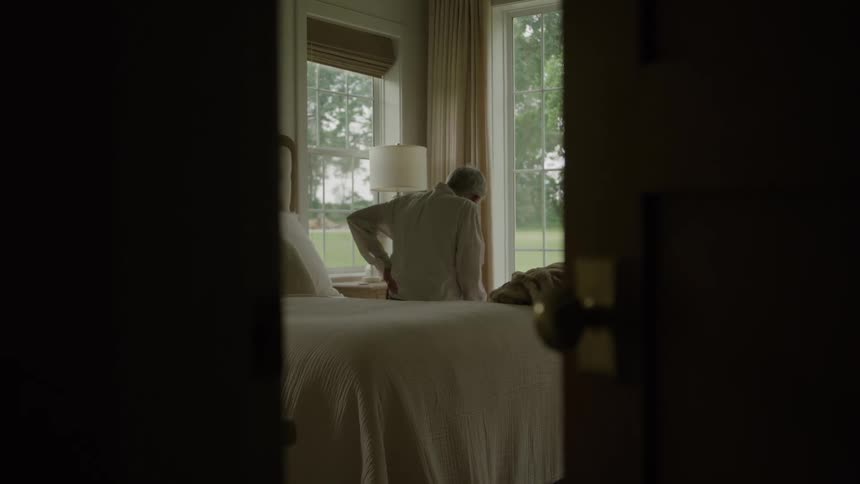 An old man sits on his bed