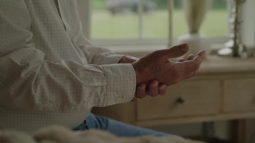 An old man holds his wrist