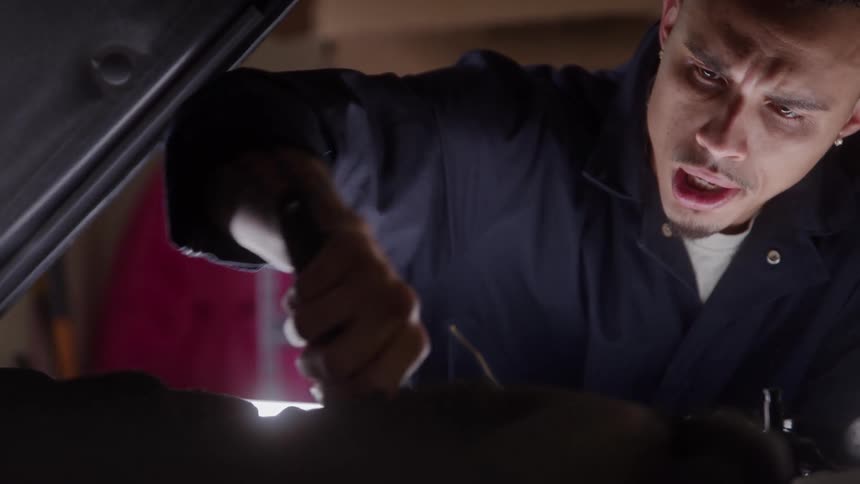 A mechanic is using a wrench to fix the engine of a car