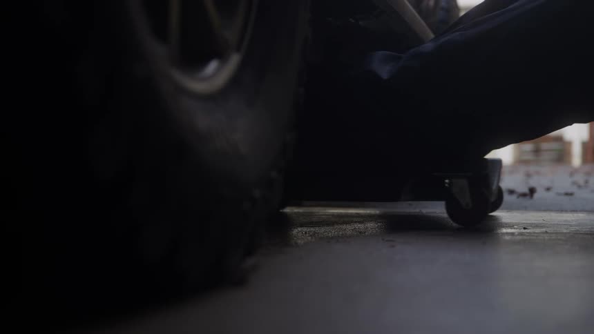 A mechanic rolls himself underneath a car