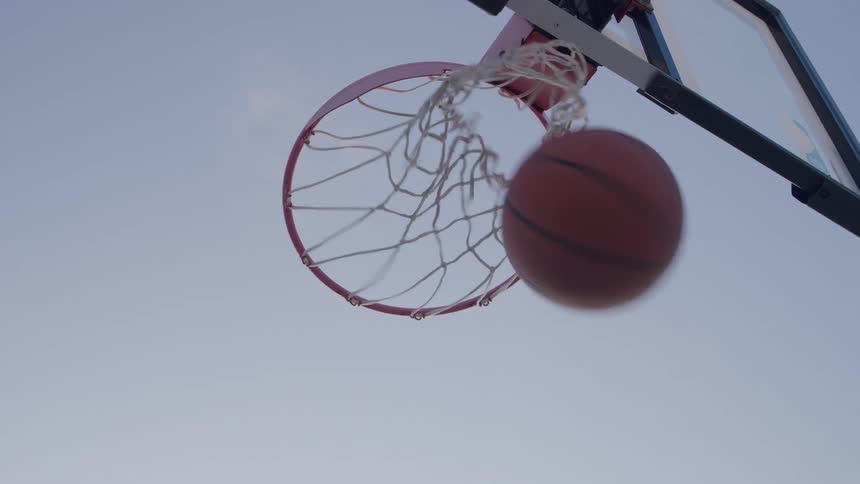 A basketball is being shot through the hoop and net