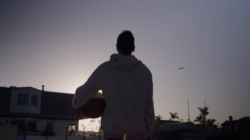 The bird flies over a woman holding a basketball