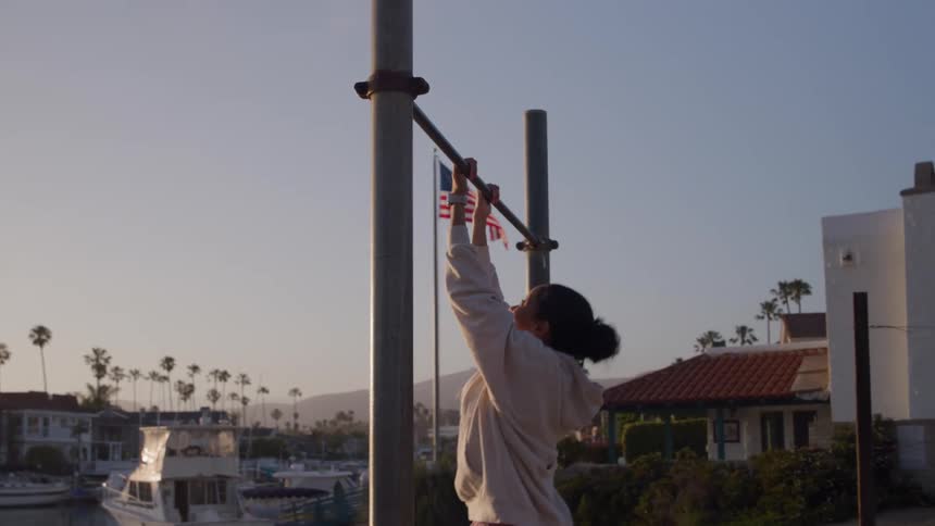 A woman doing pullups on an outdoor iron bar