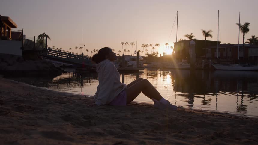 A girl sitting on a beach at dusk