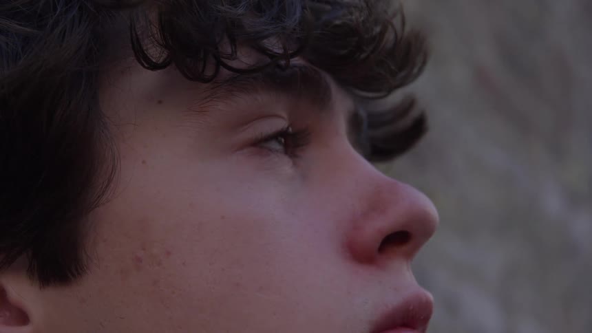 A tear wells up in the eye of a young man as he looks upward