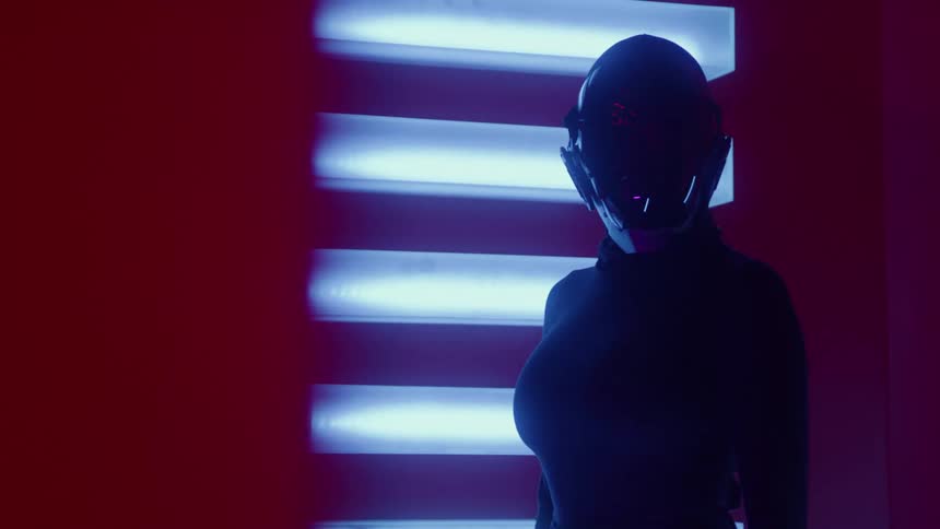 Door opens and a woman wearing a robotic helmet stands next to an illuminated wall