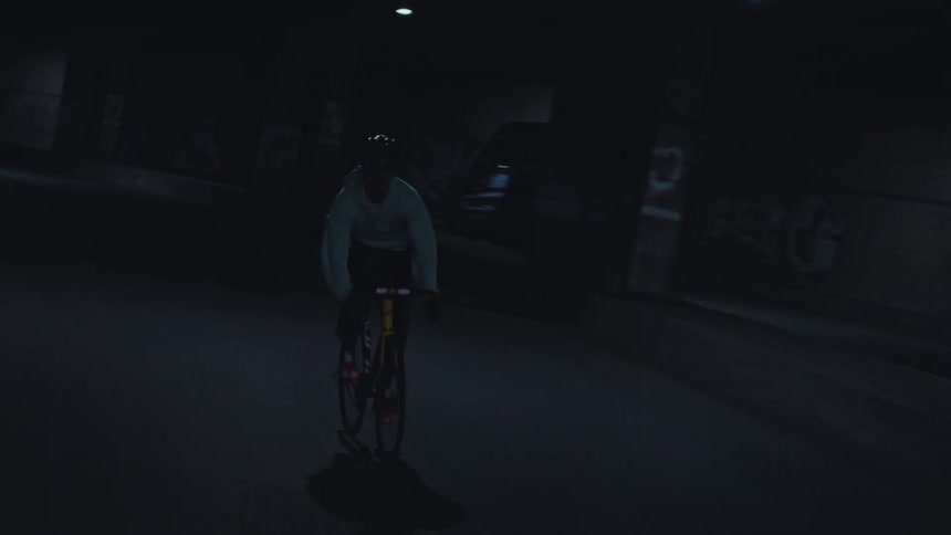 A young man riding a bicycle on a road inside a city tunnel