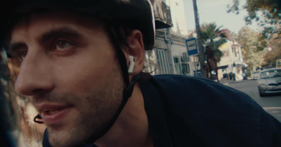 Male cyclist smiles while cycling along a street on an autumn day