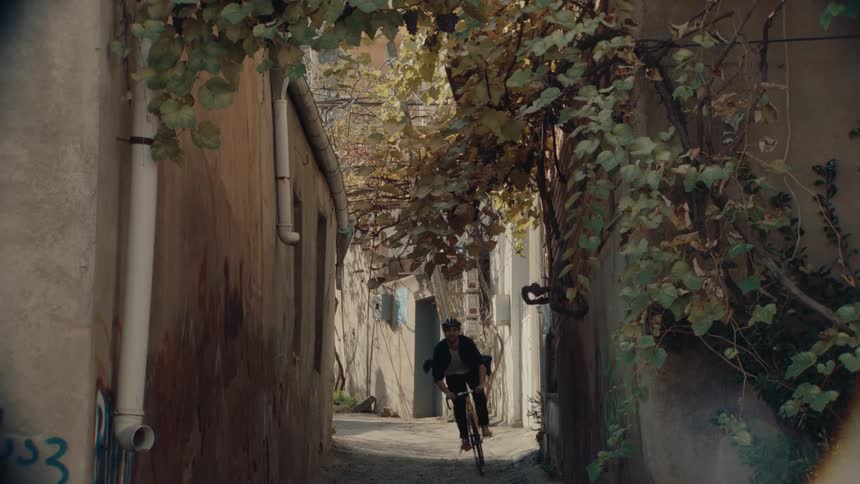 Man rides his bicycle on a neighborhood alley between buildings